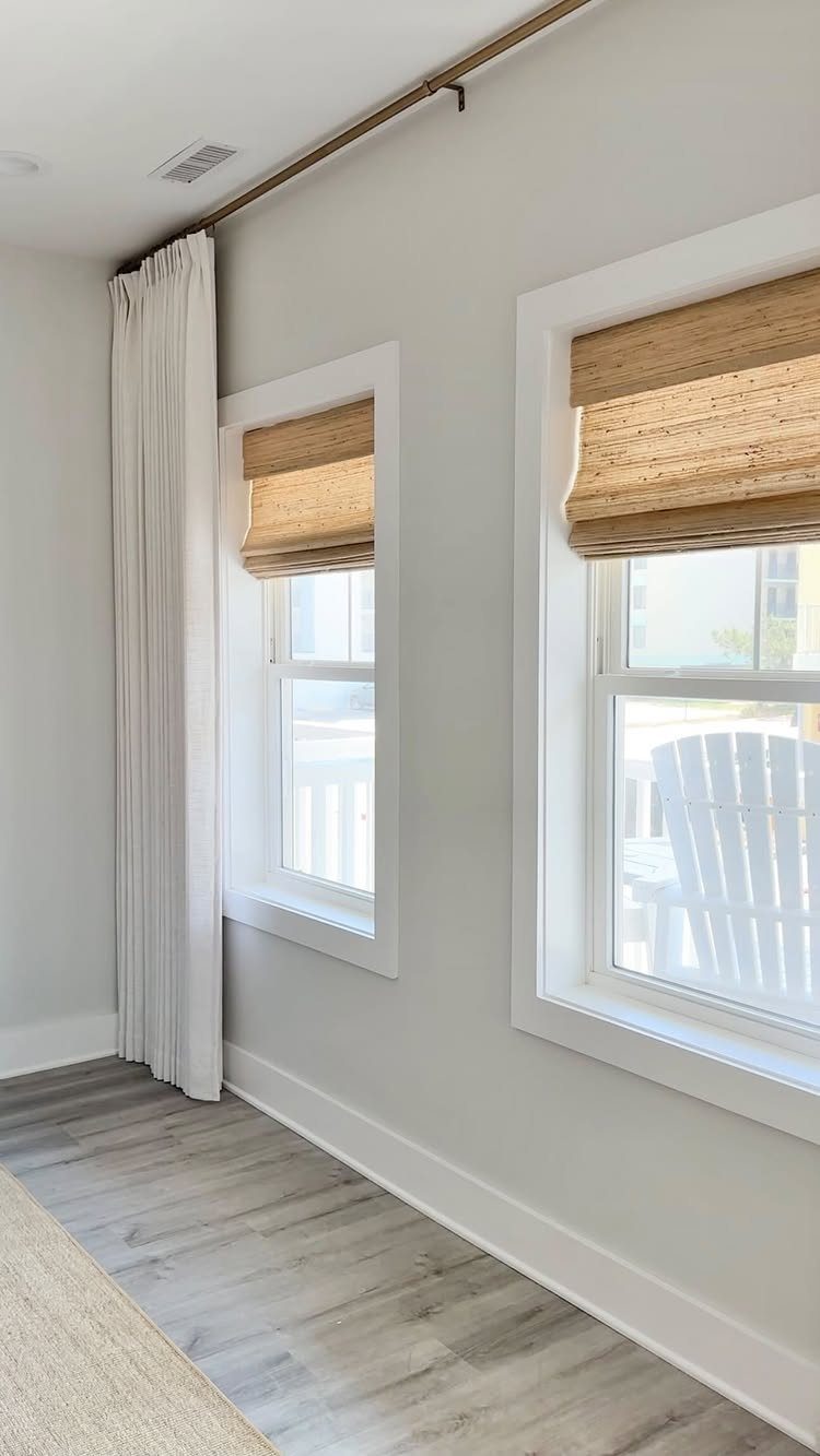 Roman Shades with Curtains: 8 Looks That Work 2 Tan woven roman shades inside window frames paired with long white curtains on an outside rod.