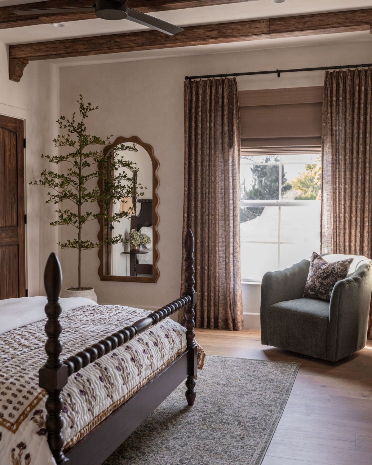 Roman Shades with Curtains: 8 Looks That Work 7 A bedroom window featuring a brown roman shade paired with long patterned curtains and a green armchair.