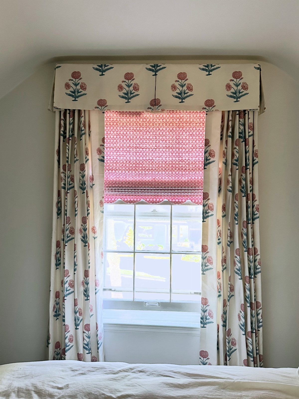 Roman Shades with Curtains: 8 Looks That Work 5 Floral patterned valance, roman shade, and matching curtains hanging over a bright window.