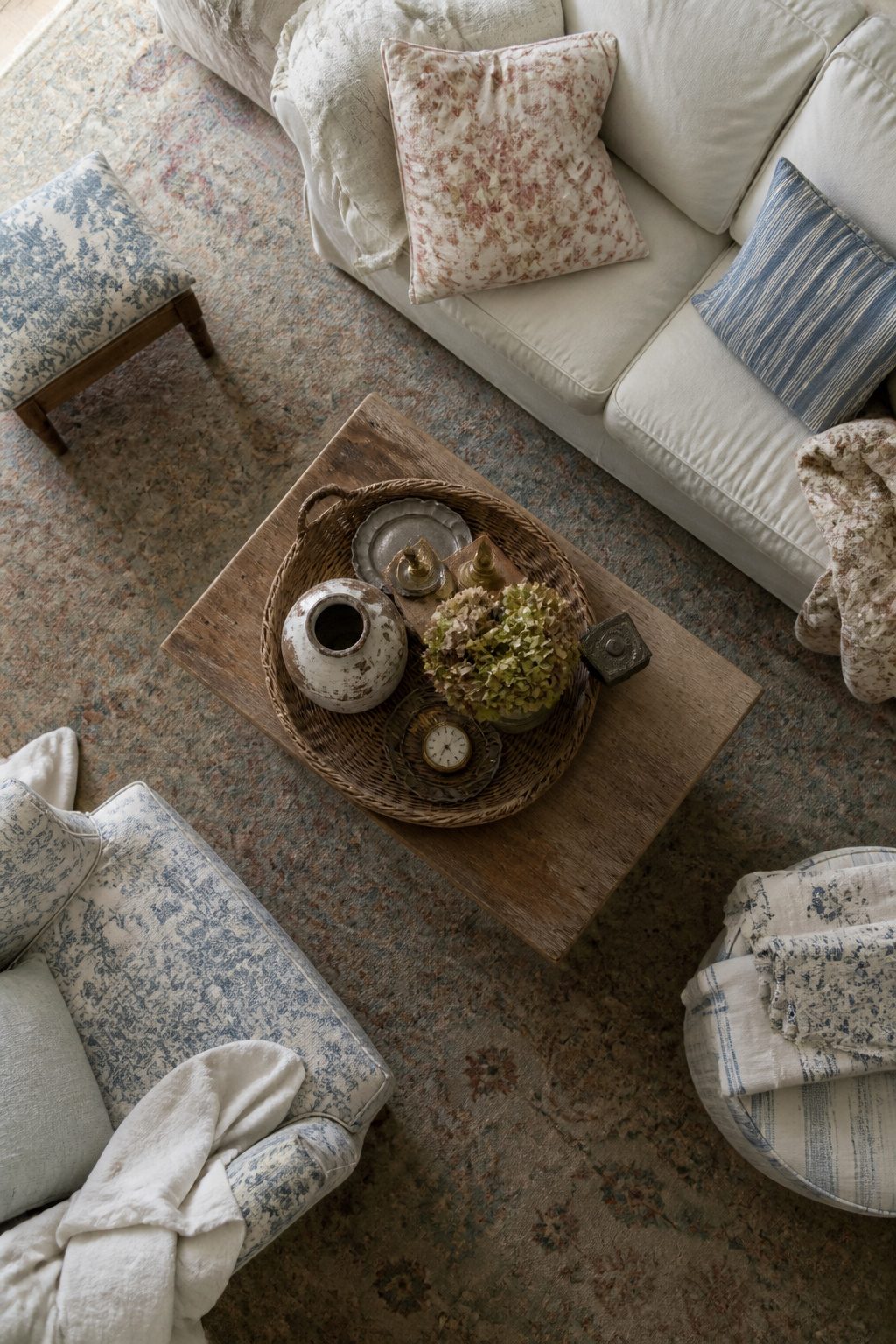 10 Shabby Chic Living Room Ideas for Soft, Lived-In Charm 4 A coffee table with a rattan tray and various eclectic decorative items.