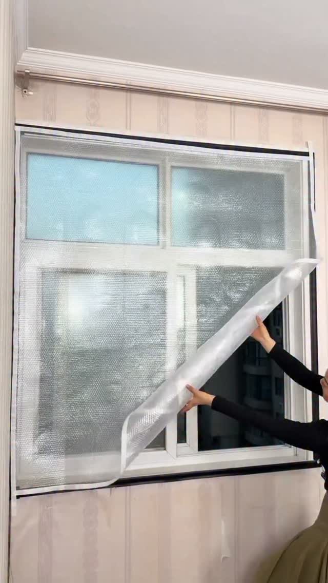 Temporary Window Privacy Ideas: 4 Ways to Block the View 4 Hands applying a sheet of bubble wrap to a large white window pane for privacy.