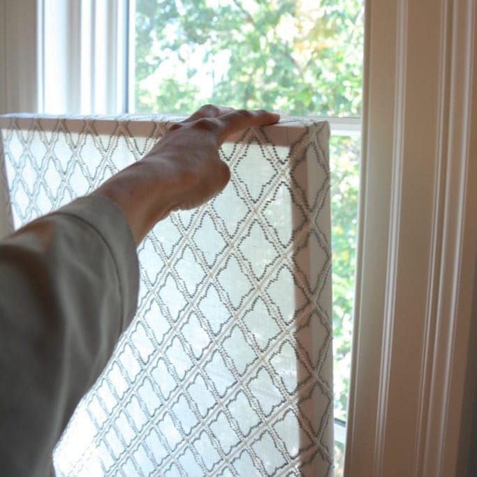 Temporary Window Privacy Ideas: 4 Ways to Block the View 3 A person holding a patterned DIY privacy window screen frame up to a bright window.