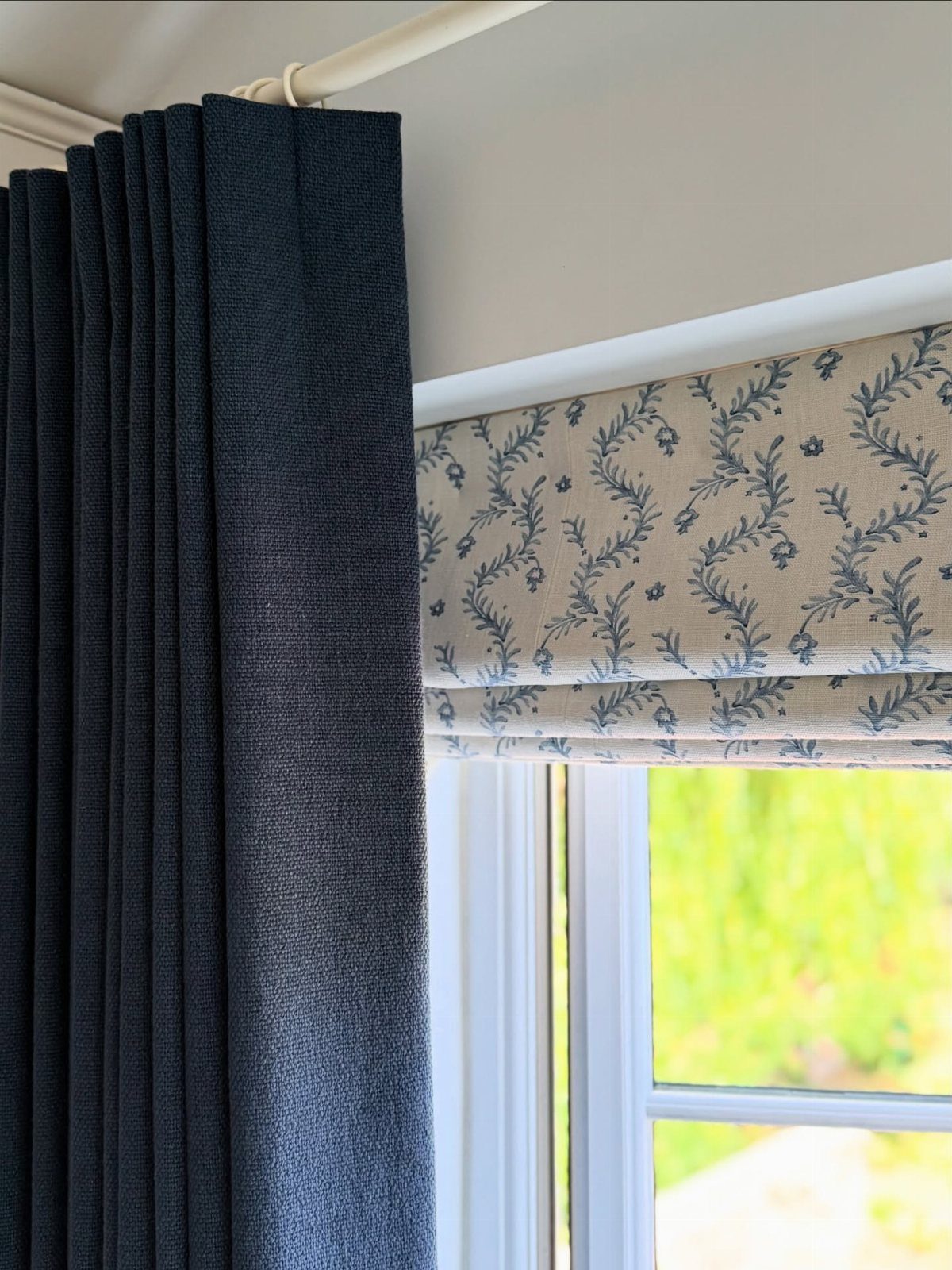 22 Unique Bedroom Curtains for Layered, Canopy and Lighted Styles 21 Dark blue textured curtains and a floral patterned Roman shade hanging by a bright window.