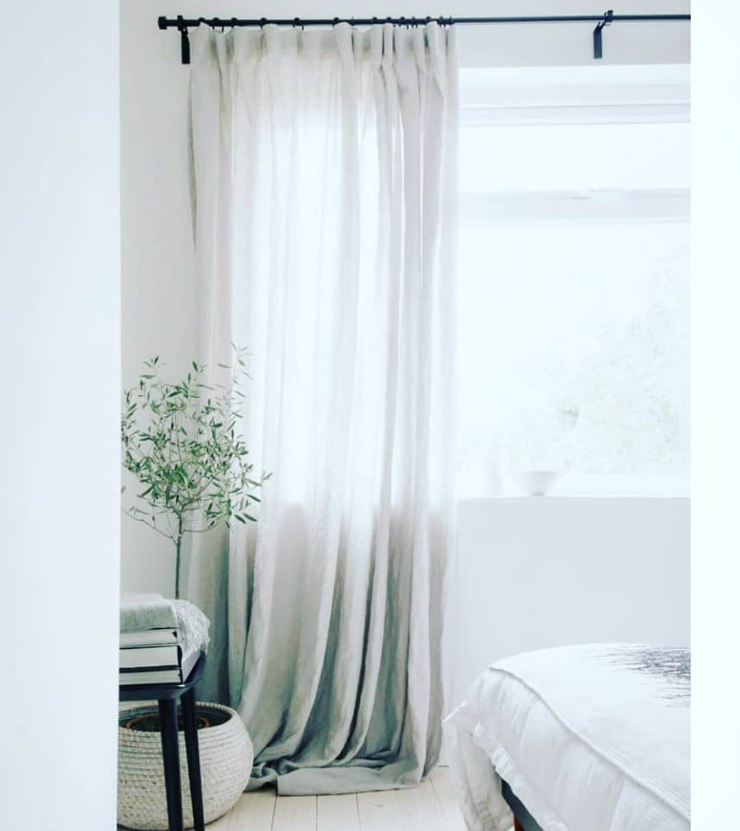 22 Unique Bedroom Curtains for Layered, Canopy and Lighted Styles 6 Sheer white curtains hanging from a black rod and puddling on a light wooden floor.