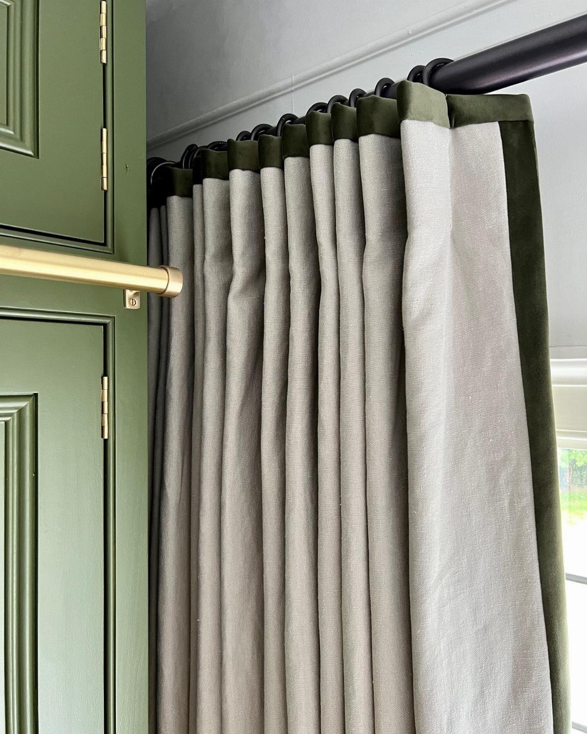 22 Unique Bedroom Curtains for Layered, Canopy and Lighted Styles 20 Grey fabric curtains with dark green velvet trim hanging from a black rod next to green cabinets.