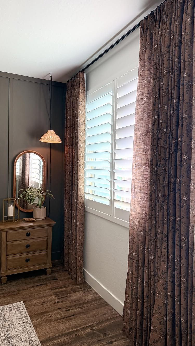 22 Unique Bedroom Curtains for Layered, Canopy and Lighted Styles 14 Brown patterned curtains framing a white shuttered window in a dark styled room.