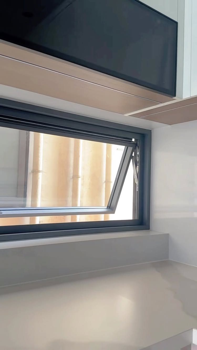 A black-framed awning window opening outward above a white kitchen countertop.