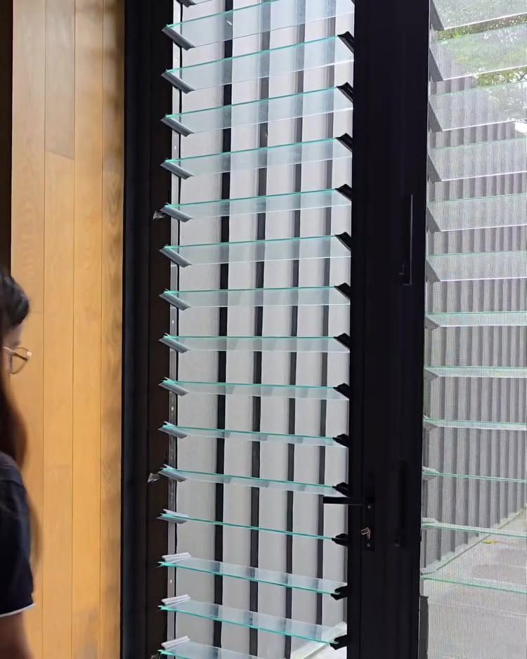 Glass louvered windows with black frames installed in a modern building structure.