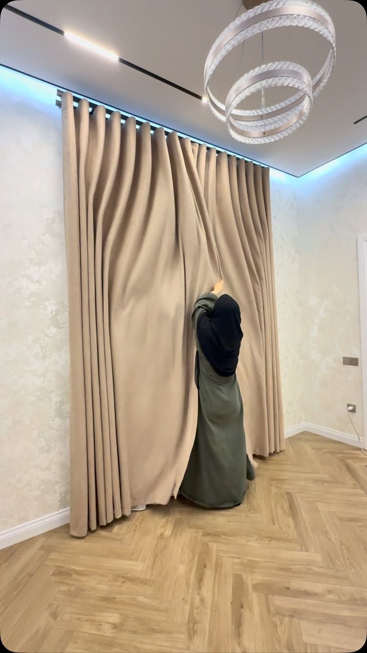 11 Ways to Style Curtains for Every Room in 2026 2 Beige floor-to-ceiling curtains hanging from a ceiling track in a modern room with herringbone floors.