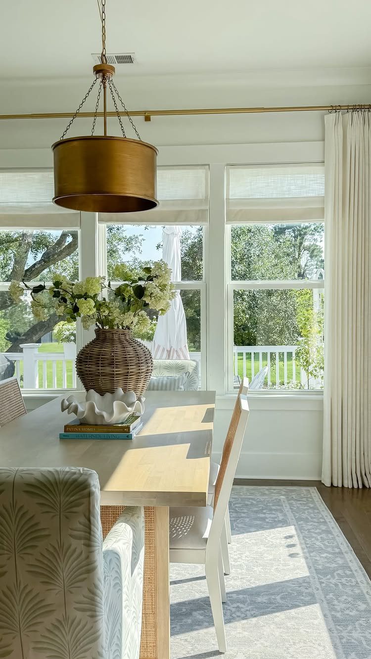 11 Ways to Style Curtains for Every Room in 2026 7 Dining room interior featuring white roman shades and long white curtains by large windows.