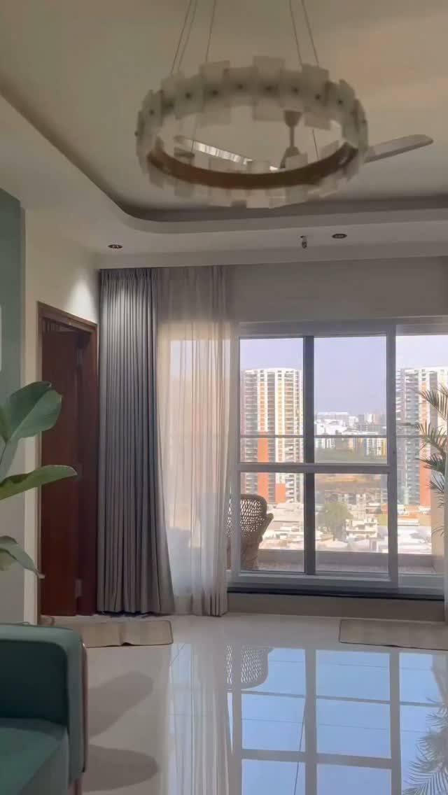 11 Ways to Style Curtains for Every Room in 2026 1 Grey pleated curtains and sheer white panels hanging from the ceiling to the floor by a window.