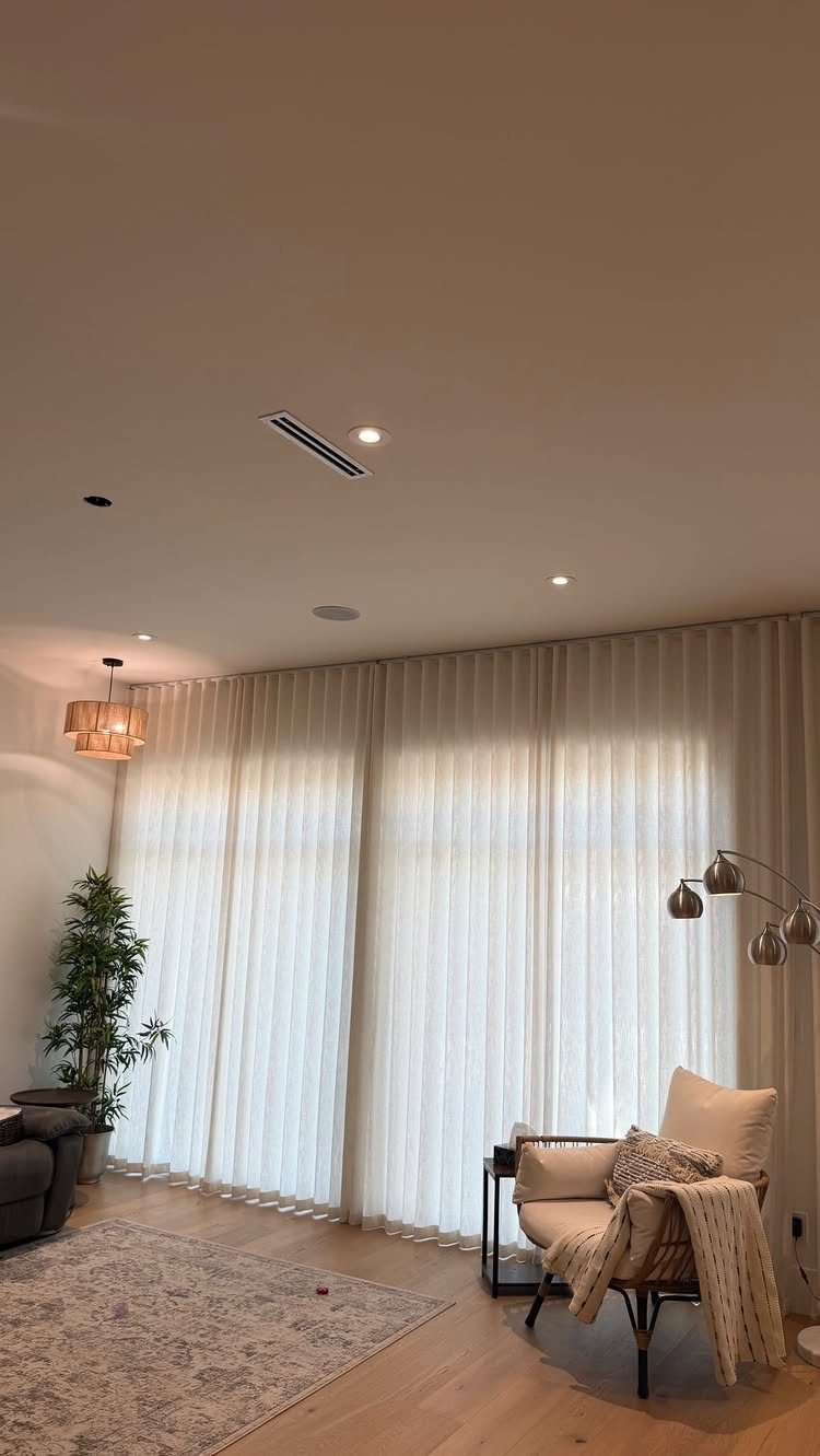 Window Blinds for Living Room: 11 Photo Ideas 11 Sheer white drapery hangs across large windows in a bright, modern living room setting.