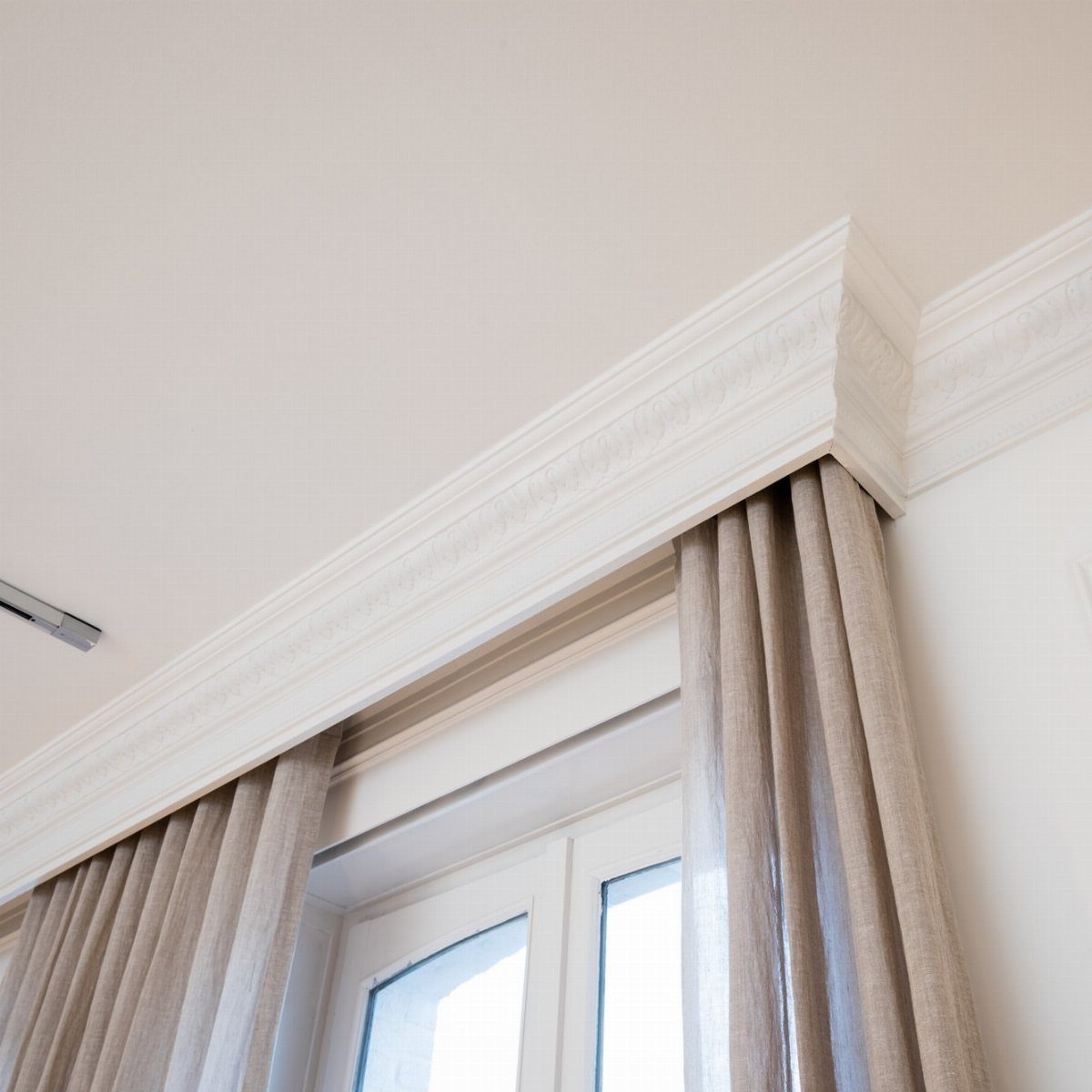 Window Cornice DIY: 5 Ways With Fabric, Wood, and Molding 3 White decorative crown molding cornice installed above beige linen curtains on a window.