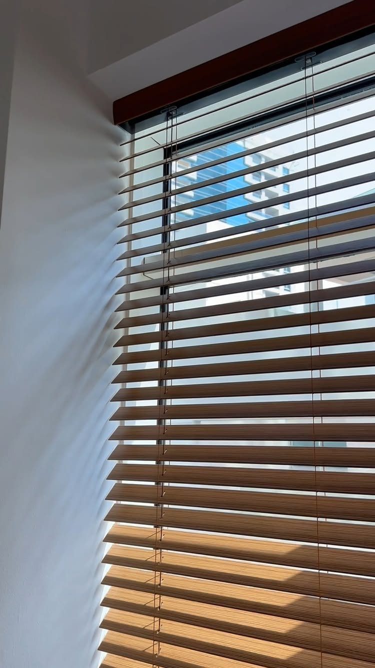10 Window Dressing Ideas for Shutters, Shades and Blinds 2 Wooden Venetian blinds installed in a window casting shadows on a white wall.