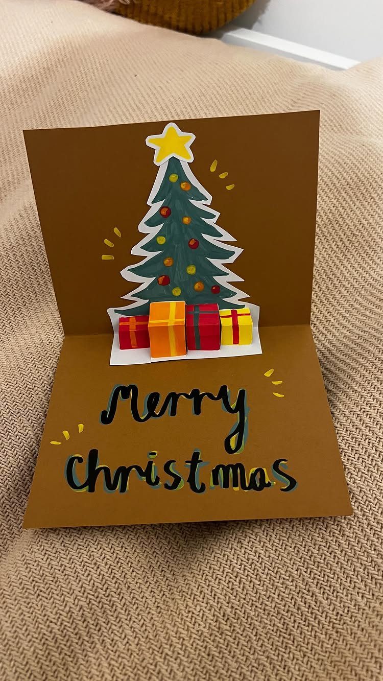 32 Xmas Gifts to Make: Easy Ideas for Handmade Holiday Presents 10 A handmade brown pop-up Christmas card with a decorated tree and Merry Christmas text.