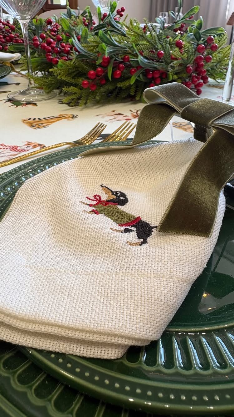 32 Xmas Gifts to Make: Easy Ideas for Handmade Holiday Presents 26 Embroidered dachshund napkin with a green velvet bow on a green plate.