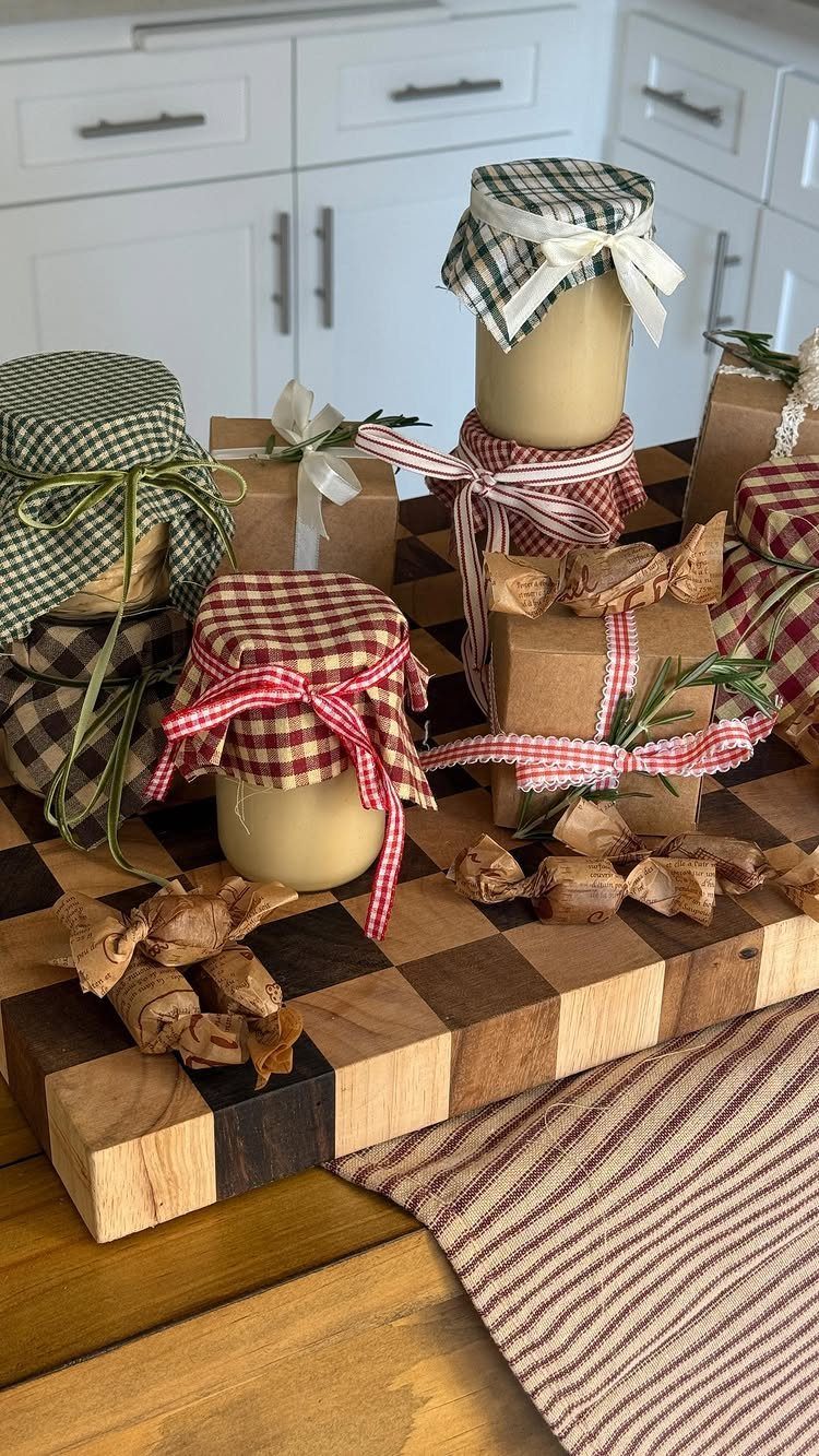 32 Xmas Gifts to Make: Easy Ideas for Handmade Holiday Presents 22 Glass jars with patterned fabric lids and ribbons arranged on a wooden checkerboard cutting board.