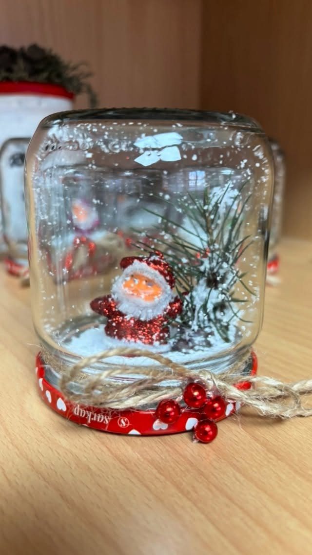 32 Xmas Gifts to Make: Easy Ideas for Handmade Holiday Presents 25 A handmade snow globe in a glass jar with a Santa figurine and pine needles.
