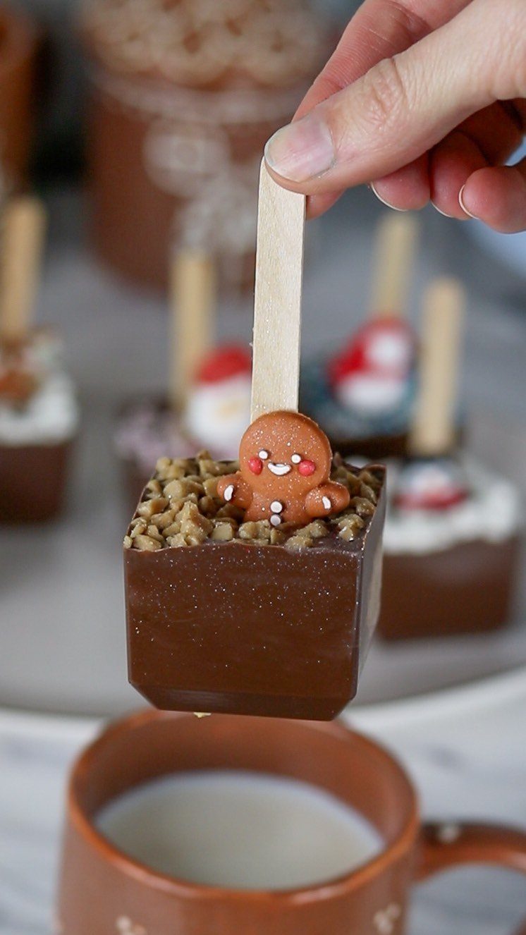 32 Xmas Gifts to Make: Easy Ideas for Handmade Holiday Presents 2 A hand holds a chocolate stirrer decorated with a gingerbread man over a mug of milk.