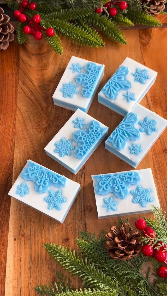 32 Xmas Gifts to Make: Easy Ideas for Handmade Holiday Presents 13 Six white snowflake-patterned lotion bars resting on a wooden table with festive greenery.