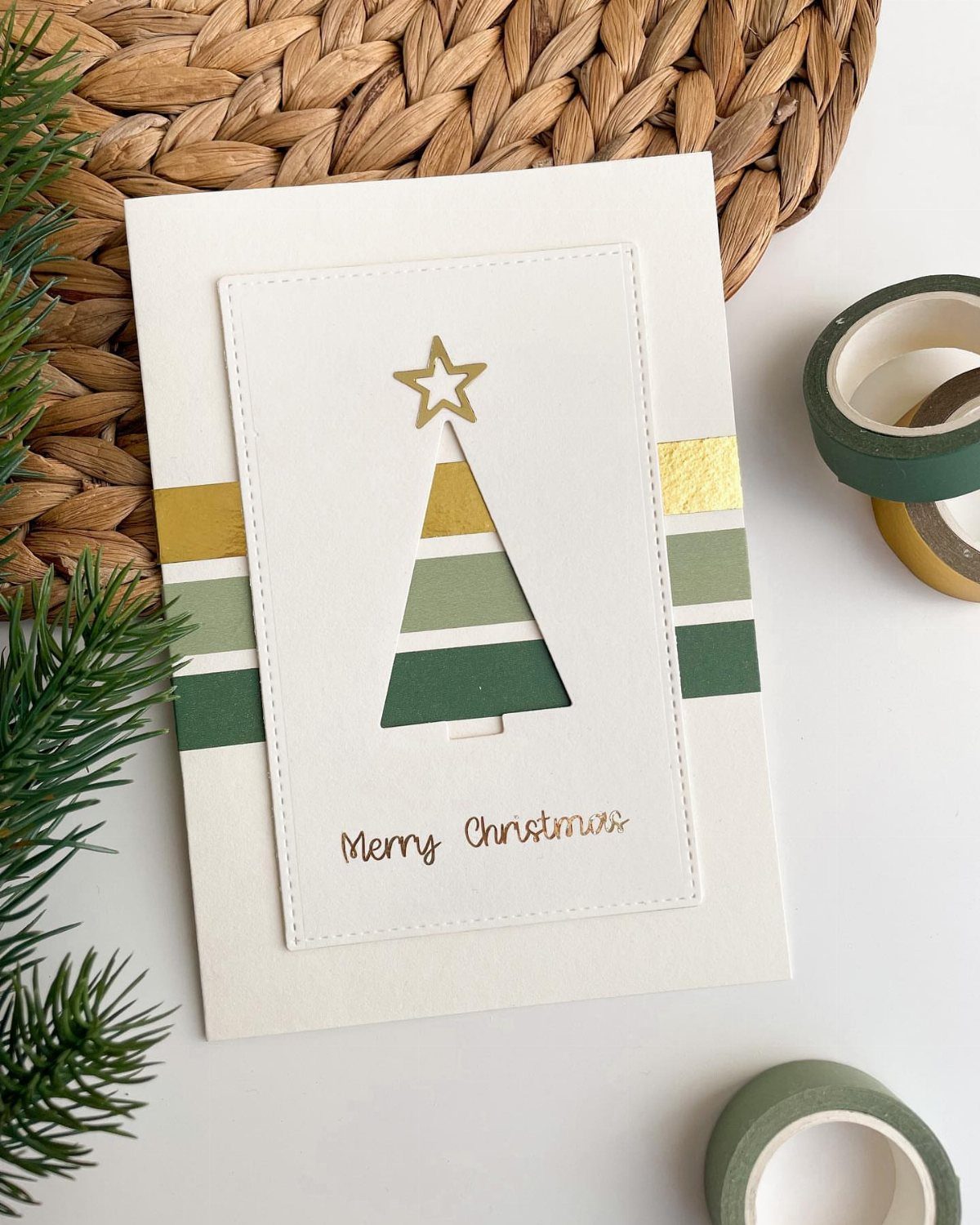 32 Xmas Gifts to Make: Easy Ideas for Handmade Holiday Presents 12 A white Christmas card with a tree cutout decorated with green and gold washi tape stripes.
